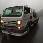 Caminhão reboque transportando um carro em um dia de chuva