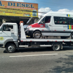 Caminhão reboque transportando uma van em cima da plataforma